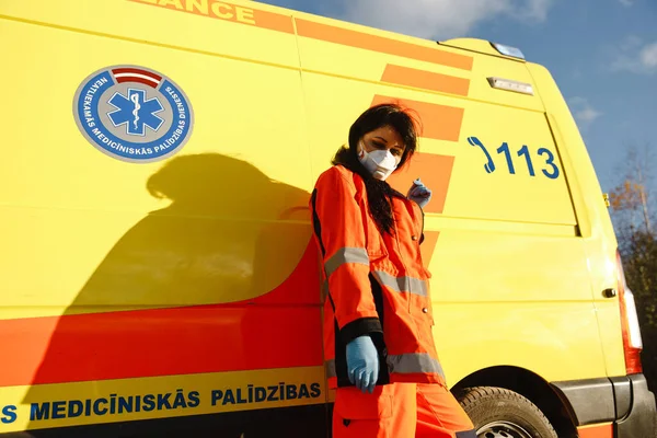 Mladá zdravotnice pózuje v blízkosti sanitního vozidla — Stock fotografie