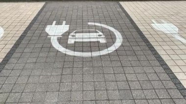 Elektrikli araba şarj parkı otoparkındaki kaldırıma tabelasını asıyor.
