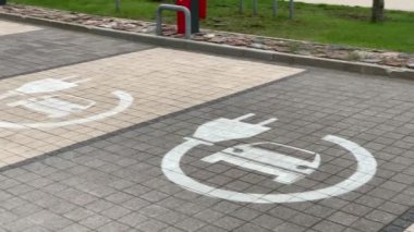 Solda: Otoparktaki kaldırımda EV şarj parkı işareti
