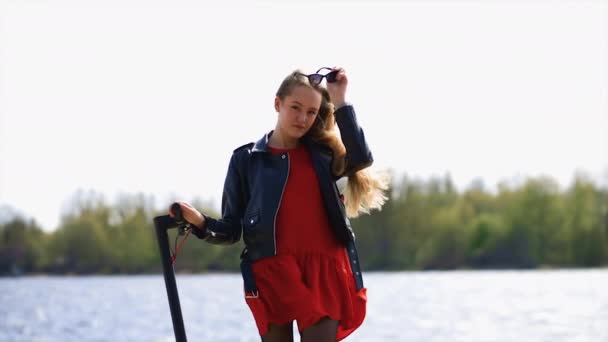 Młoda stylowa kobieta portret z elektrycznym skuterem na promenadzie — Wideo stockowe