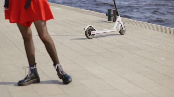 Scooter elettrico bianco sul lungomare vicino al fiume con gambe femminili in primo piano — Video Stock