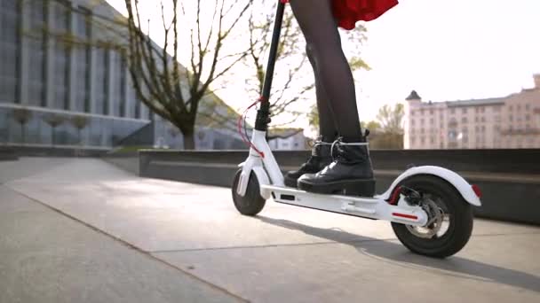 Žena v černých botách jezdí na elektrickém skútru. Velmi nízká gimbal následovat výstřel — Stock video