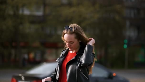 Mladá stylová žena stojí a drží elektrický skútr ve městě ulici — Stock video