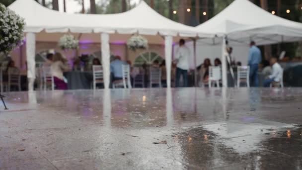 Desenfocado: Grupo de personas celebrando y festejando en tiendas al aire libre durante la lluvia — Vídeos de Stock