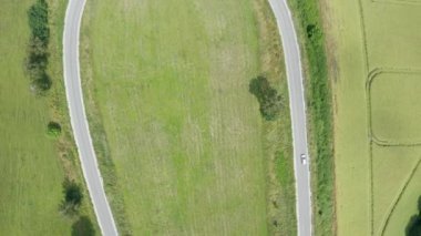 Polonya 'nın Warmia bölgesindeki kavisli yolun yukarıdan aşağıya insansız hava aracı görüntüsü