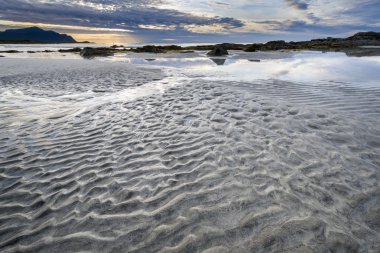 Gün batımından bir kumsalda Lofoten adalar üzerinde