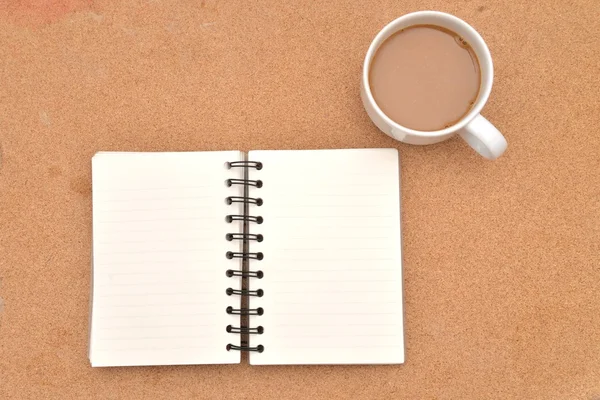 Almofada de nota em espiral em branco, xícara de café em fundo de madeira . — Fotografia de Stock