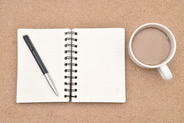 Note a spirale bianca, tazza di caffè e penna su sfondo legno . — Foto Stock