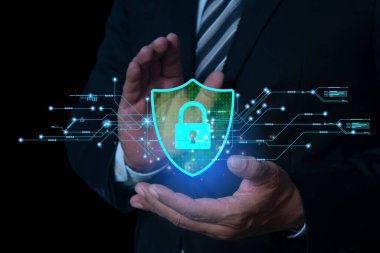 Koruma kalkanı ikonu elinde tutan bir iş adamı, koruma ağı güvenlik bilgisayarı ellerinde. Korsan saldırılarından korunan kalkan internet, gizlilik ağı