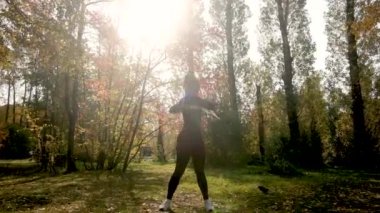 Güzel kız parkta jimnastik yapıyor. Sonbahar ormanlarında sağlık, sakinlik ve farkındalık, meditasyon, esnek vücut. aktif yaşam tarzı konsepti. Plaj sezonuna hazırlanıyorum.