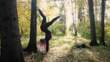 Güzel kız parkta jimnastik yapıyor. Sonbahar ormanlarında sağlık, sakinlik ve farkındalık, meditasyon, esnek vücut. aktif yaşam tarzı konsepti. Plaj sezonuna hazırlanıyorum.