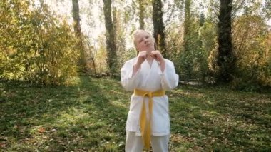 On iki yaşındaki genç bir kız parkta karate yapıyor. Sağlıklı yaşam tarzı kavramı. Spor yapıyor. Dövüş sanatları. Judo, Jiujitsu. Cesur, güçlü. Boyun egzersizi yapıyor. alıştırmalar