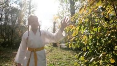 12 yaşındaki genç kız dışarıda karate yapıyor. Sağlıklı yaşam tarzı kavramı. Spor yapıyor. Dövüş sanatları. Judo, Jiujitsu. Cesur, güçlü. Parkta gülümseyen yürüyüşler. alıştırmalar