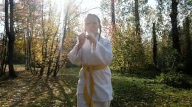 On iki yaşındaki genç bir kız parkta karate yapıyor. Sağlıklı yaşam tarzı kavramı. Spor yapıyor. Dövüş sanatları. Judo, Jiujitsu. Cesur, güçlü, tekmelerini çalıştırıyor. Çalışmalar