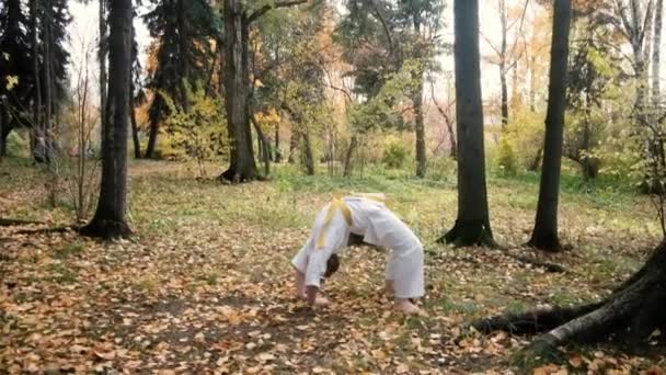 Tonårstjej 12 år gammal är engagerad i karate utomhus i parken. Friska livsstil koncept. Spelar sport. Kampsporter. Judo och Jiujitsu. djärv, stark, gör övningar. Träning — Stockvideo