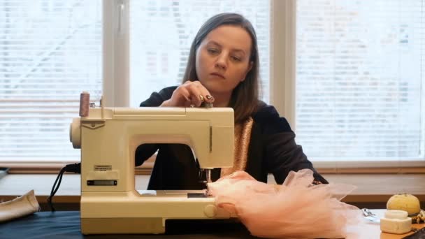30-letnia krawcowa szyje na maszynie do pisania. Projektant odzieży. W trakcie pracy w fabryce. Kobieta krawiec robi modne ubrania w warsztacie. Zawód. styl mody — Wideo stockowe
