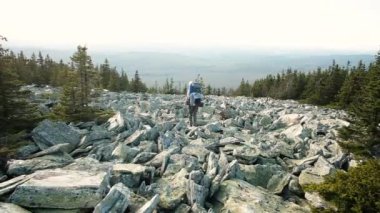 Seyahat yaşam tarzı. Hayatta kalma kavramı. Sırt çantalı bir turist, sıcak bir yaz gününde, uzun bir yürüyüş için dağlarda yürür. Kayalar, dağlar. spor.