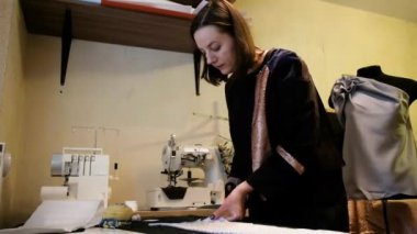 Kumaşı makasla keser. Modelci kadın atölyesinde yeni bir elbise üzerinde çalışıyor. Yaratıcı bir tasarım stüdyosunda çalışıyorum. Yeni bir kıyafet koleksiyonu..