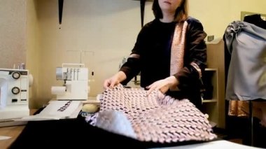 Kadın moda tasarımcısının atölyesinde yeni bir elbise üzerinde çalışması için kumaş serpiştiriyordu. Yaratıcı bir tasarım stüdyosunda çalışıyorum. Yeni bir kıyafet koleksiyonu..