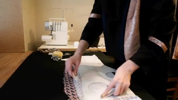 La mujer hace el corte de la tela por el patrón. Mujer diseñadora de moda trabaja en un nuevo vestido en su taller. Trabaja en un estudio de diseño creativo. El concepto de una nueva colección de ropa. — Vídeos de Stock