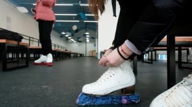 Women put on skates. Close-up. Weekend at the rink. Winter sports. Blade.Lacing. Preparation before going on the ice. Active lifestyle concept. shoes, legs.