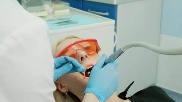 Fermer les mains de dentistes féminines dans des gants stériles pour traiter le patient à l'aide d'une perceuse. stomatologue professionnel dans le masque de perçage des dents à la cliente. soins, traitement. bur, conseils — Video