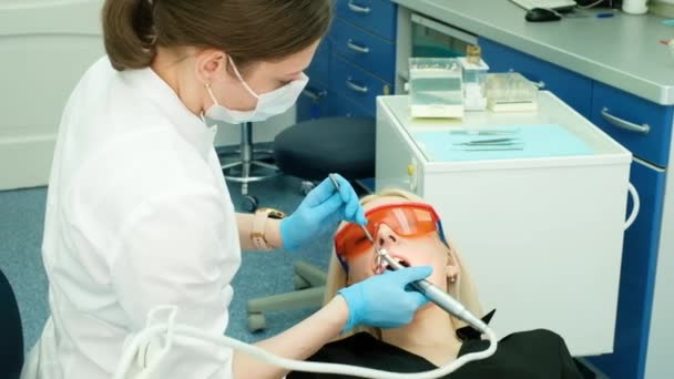 Fermer les mains de dentistes féminines dans des gants stériles pour traiter le patient à l'aide d'une perceuse. stomatologue professionnel dans le masque de perçage des dents à la cliente. soins, traitement. bur, conseils — Video