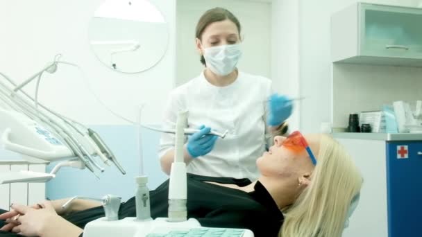 Mãos de dentista feminino em luvas estéreis fazendo tratamento para o paciente usando máquina de broca. Estomatologista profissional em dentes de perfuração máscara para cliente feminino. cuidados, tratamento. bur, dicas — Vídeo de Stock