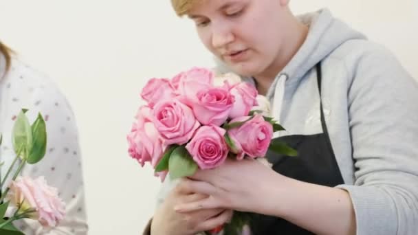 Mujer florista hace diseño floral. La práctica de hacer hermosos ramos de flores por jóvenes profesionales. Trabajo en una florería. preparación para unas vacaciones, boda, aniversario — Vídeo de stock