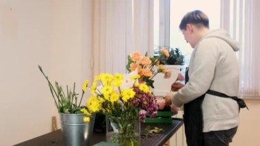 Çiçekçi kadın çiçek tasarımı yapıyor. Genç profesyoneller tarafından güzel çiçek buketleri yapma pratiği. Çiçekçide çalışıyorum. Tatil hazırlığı, düğün, yıldönümü