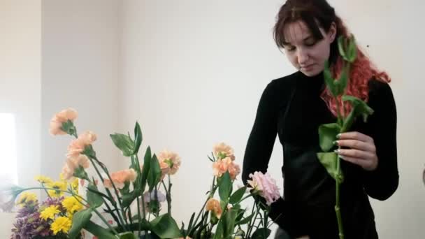 Florista mulher faz design floral. A prática de fazer belos buquês de flores por jovens profissionais. Trabalhar numa florista. preparação para umas férias, casamento, aniversário — Vídeo de Stock