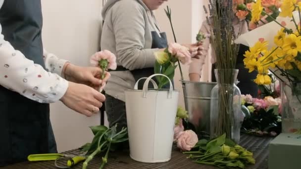 Close-up. Female florist makes floral design. The practice of making beautiful flower bouquets by young professionals. Work in a flower shop. preparation for a holiday, wedding, anniversary — Stock Video