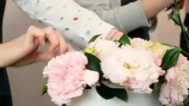 Yakın plan. Çiçek tasarımı yapan kadın çiçekçiler. Genç profesyoneller tarafından güzel çiçek buketleri yapma pratiği. Çiçekçide çalışıyorum. Tatil hazırlığı, düğün, yıldönümü