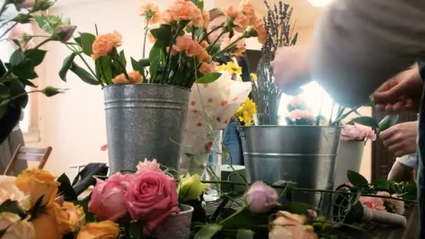 Zbliżenie. Kobieta kwiaciarnia robi kwiatowe wzory. Praktyka tworzenia pięknych bukietów kwiatów przez młodych profesjonalistów. Praca w kwiaciarni. przygotowanie do urlopu, ślubu, rocznicy — Wideo stockowe