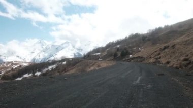 Dağlık arazide, karlı bir dağın arka planına çarpan off-road aracı. Kayalık arazi. Macera, seyahat. Çakıl taşı yolu. Engelleri aşmak, aşırı, tatil