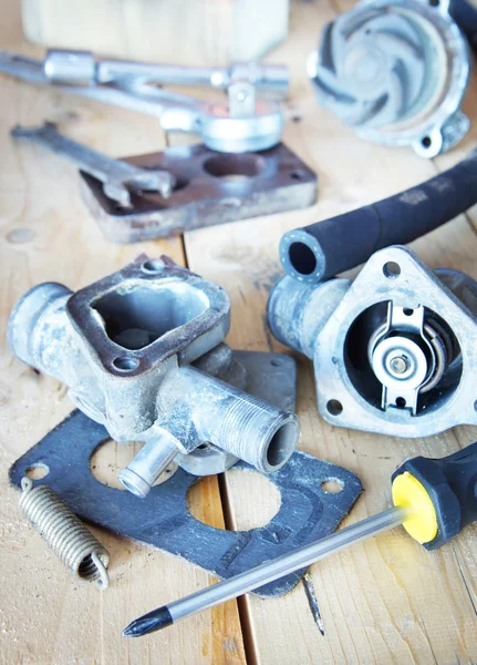 Various automobile spare parts lie on the wooden workbench