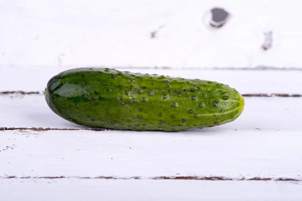 Green cucumber on old boards — Stock Photo, Image