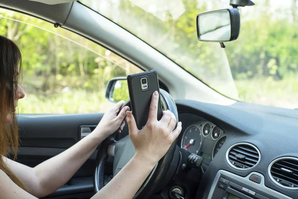 Woman with a smartphone in the car — Stock Photo, Image