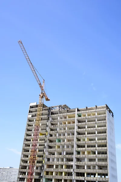 Demolição de um arranha-céu com um guindaste alto — Fotografia de Stock