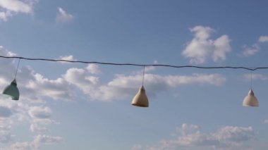 Teldeki fenerler. Mavi gökyüzü ile dekorasyon lambaları. Elektrik kablolarından sarkıyor.