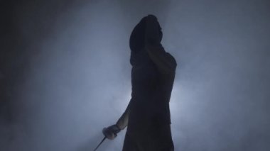 Kılıç ustası. Eskrim sporcusu. Kılıçlı bir adam. Dövüş pozisyonu. Kılıç. Maske takar.
