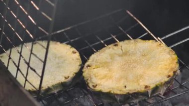 Izgara ananas dilimleri. Izgarada kızartılmış ananas dilimi, yakın çekim, dumanın yavaş çekim görüntüsü. Barbekü.