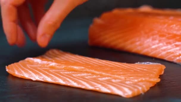 Male chef puts a fresh fillet on the table in the sushi bar, restaurant. Cooking fish in kitchen. Food ingredients for gourmets. Japanese cuisine. Serving the dish. — Stock Video