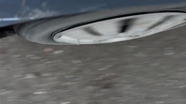 Asfalt üzerinde dönen yakın çekimli araba tekerleği, dağınık yapraklar ve toprak ile bulanık hareket, görünür jant kapağı ve kenar