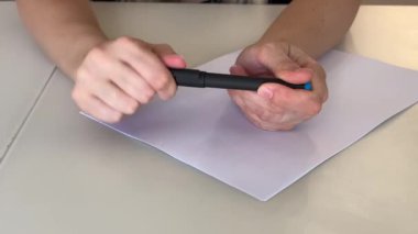 Masa başındaki beyaz kağıdın üzerinde beyaz kalem tutan beyaz eller dikkatli bir teftiş, parmak ucu ayarlaması, nazikçe