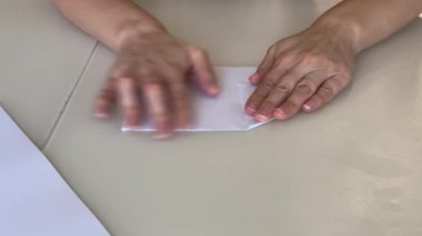 El katlayan kağıt uçak masa beyaz çarşafta darta dönüştürülmüş basamaklı kırışıklıklar, kapalı parmaklar kıvrımlar,