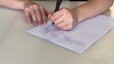 Siyah kalemle kağıda imza atan eller, beyaz belgeye gergin uygulama vuruşları, mürekkebe basan yetişkin parmaklar.,