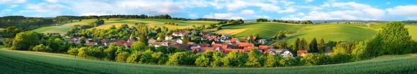 Panorama of a small village surrounded by green hills — Stock Photo, Image