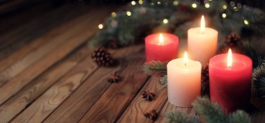Candles on a rustic wooden table with copy space. Tranquil Christmas mood with burning Advent candleflames and fir branches