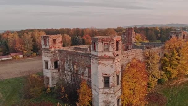 ポーランドの美しい秋の風景の中にある古い城の遺跡のドローン空中撮影カラフルな木と日没の空 — ストック動画